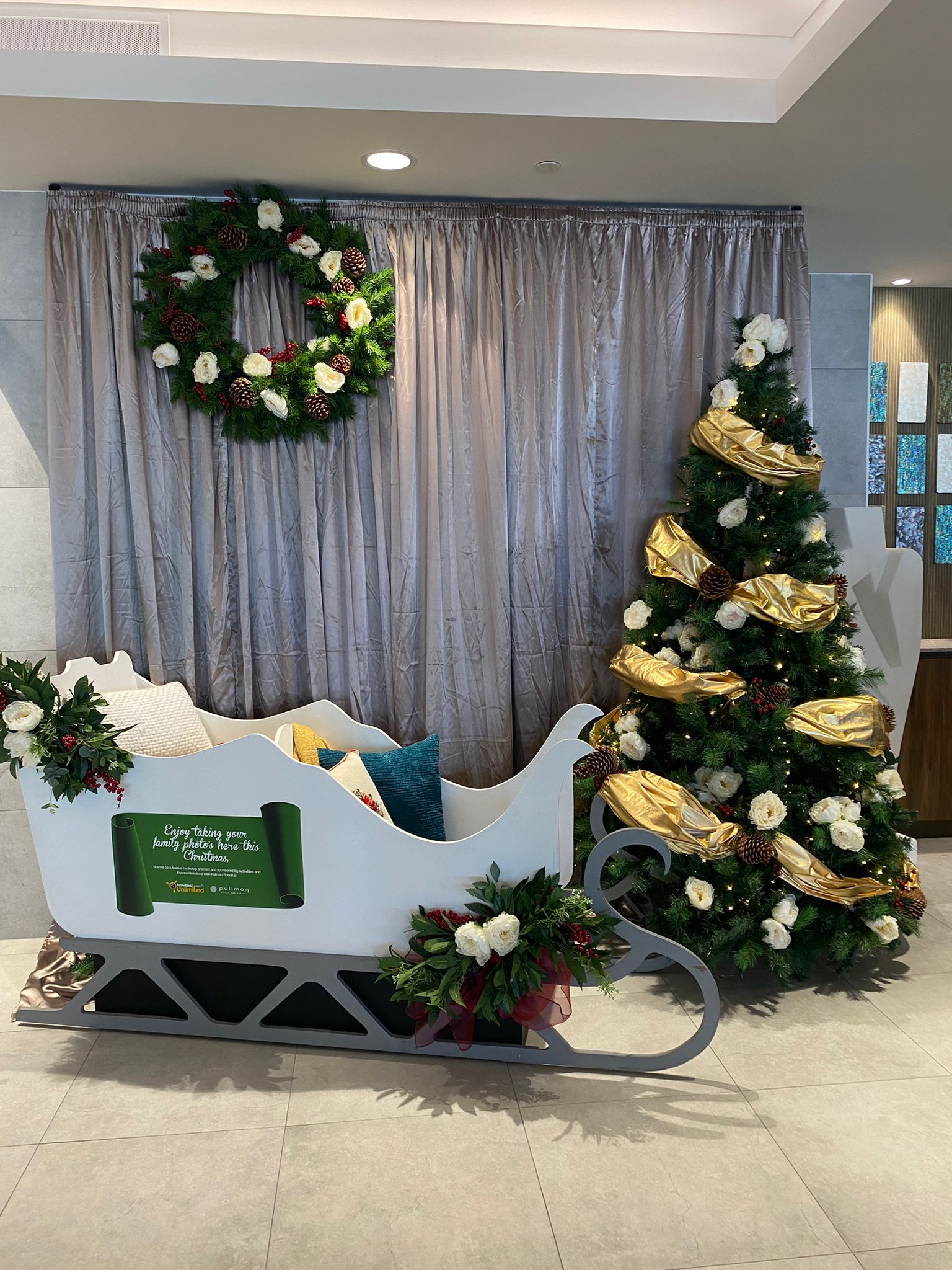 A photo of the sleigh, Christmas tree, and greenery on the Christmas set at Pullman Rotorua