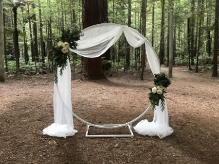 White wedding archway hoop including white organza draping and simple arrangements